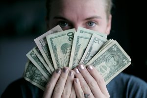 A girl holding dollar bills that will go t owards her moving budget.